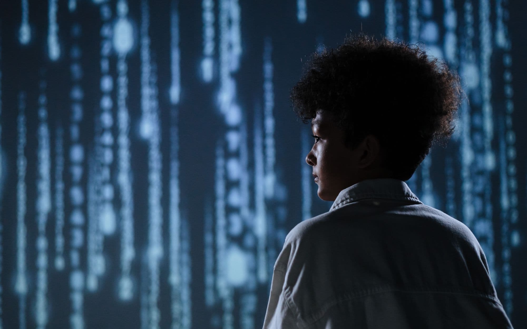 A child in profile against a wall of glowing blue digital code