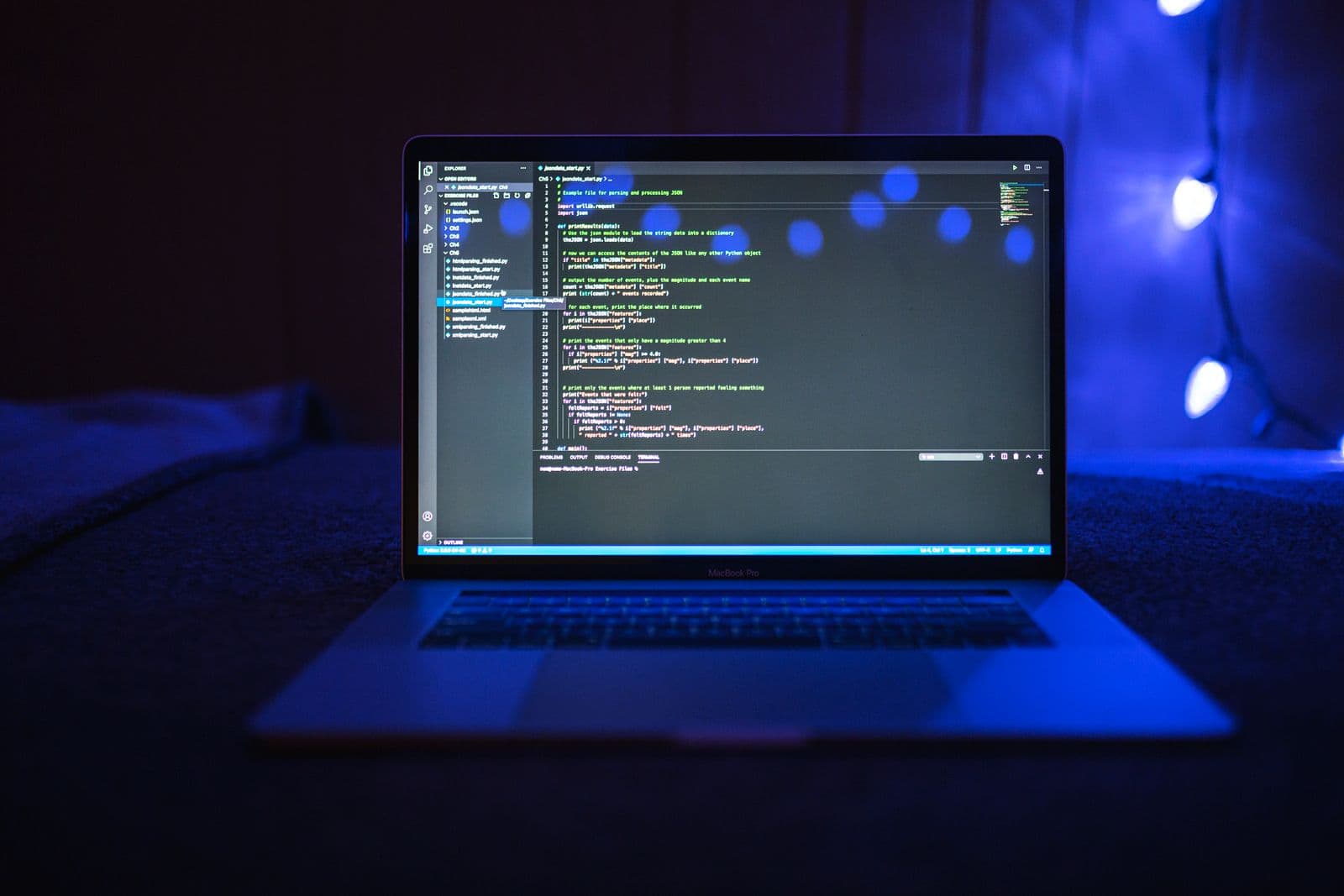 Programming code on a laptop screen lit with blue tones in a dark, focused coding setup.